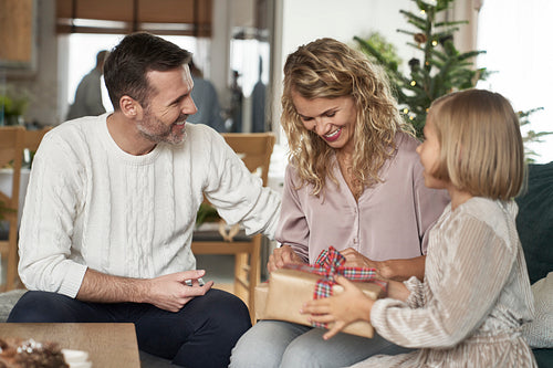 Elegant caucasian family of parents and girl sitting and sharing Christmas presents