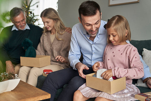 Cheerful multi generation caucasian family opening Christmas presents at home