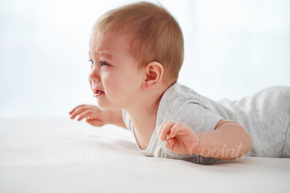 Crying baby lying on the bed