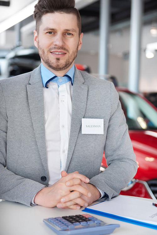 Car salesman standing in automobile showroom