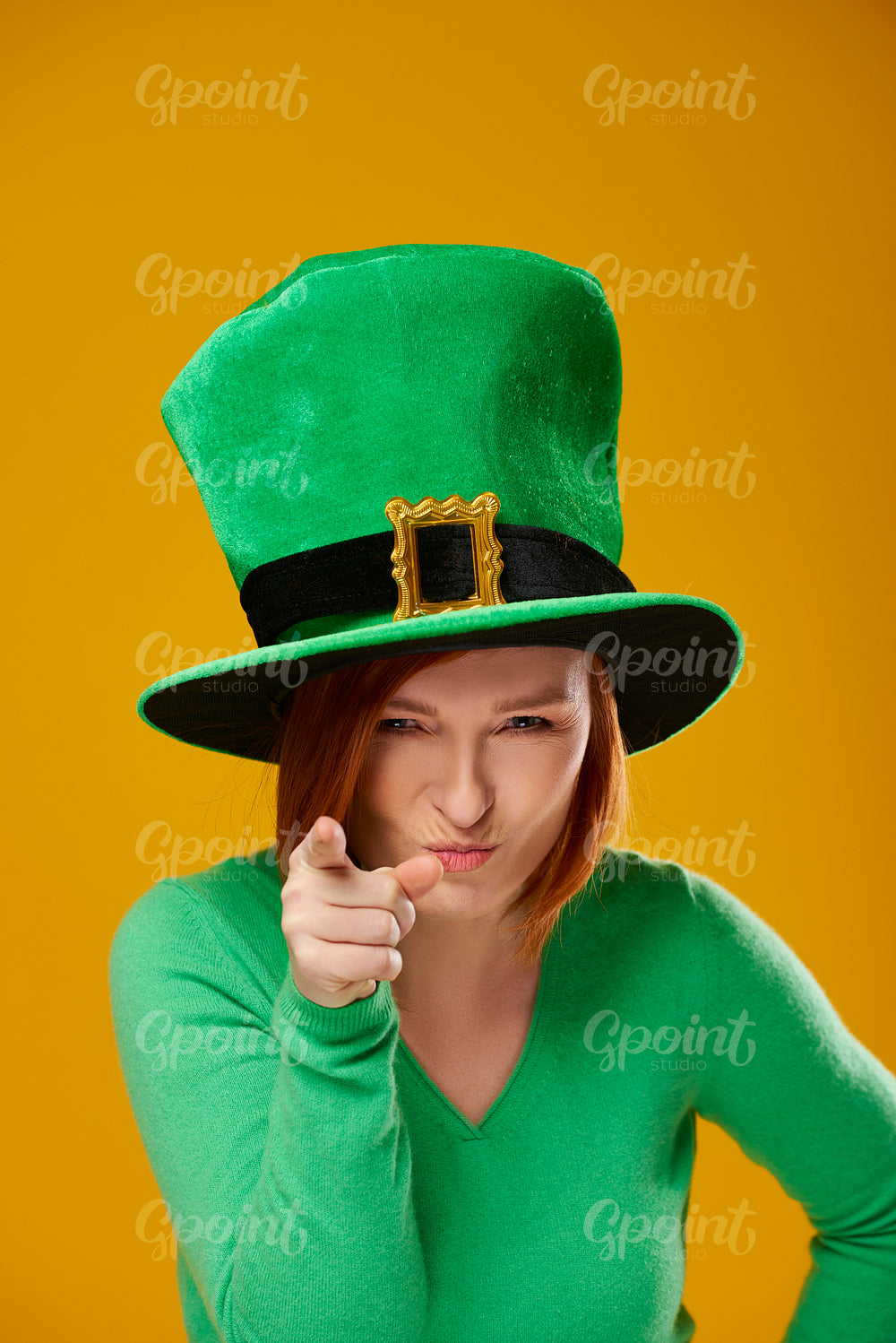 Portrait of playful woman with leprechaun's hat pointing at camera