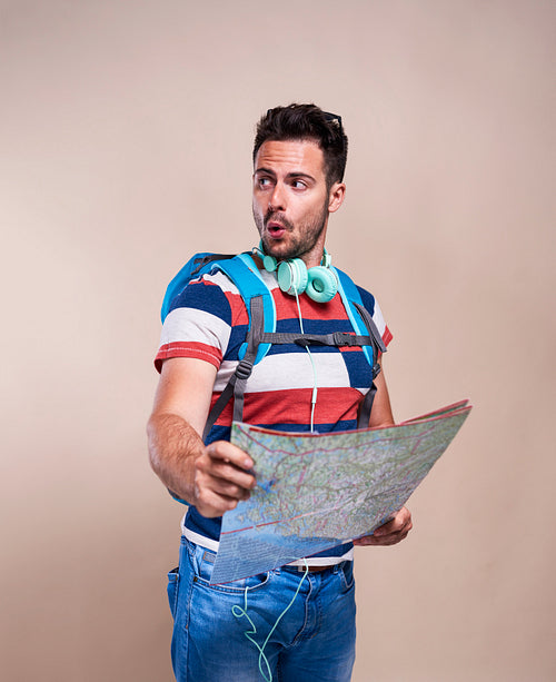 Male tourist with backpack reading a map