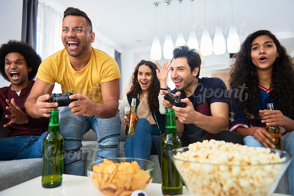Friends have fun during playing on the console at home
