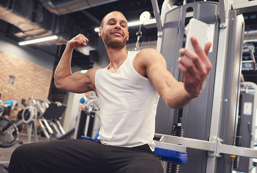 Young man tightening muscles over taking selfie