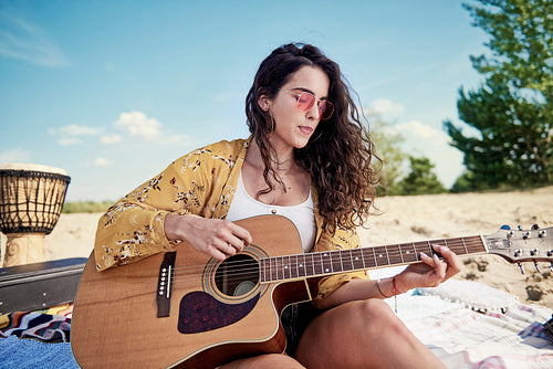 Beautiful woman playing the guitar on the beach