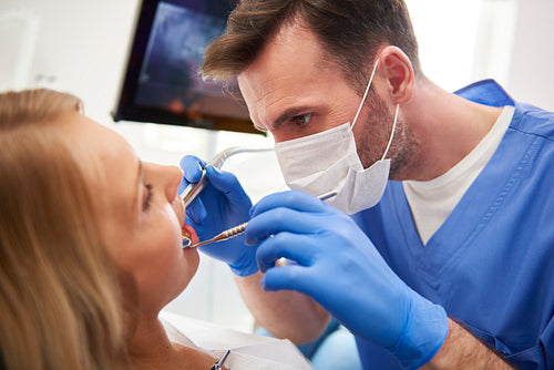 Focused stomatologist treating woman for dental cavity