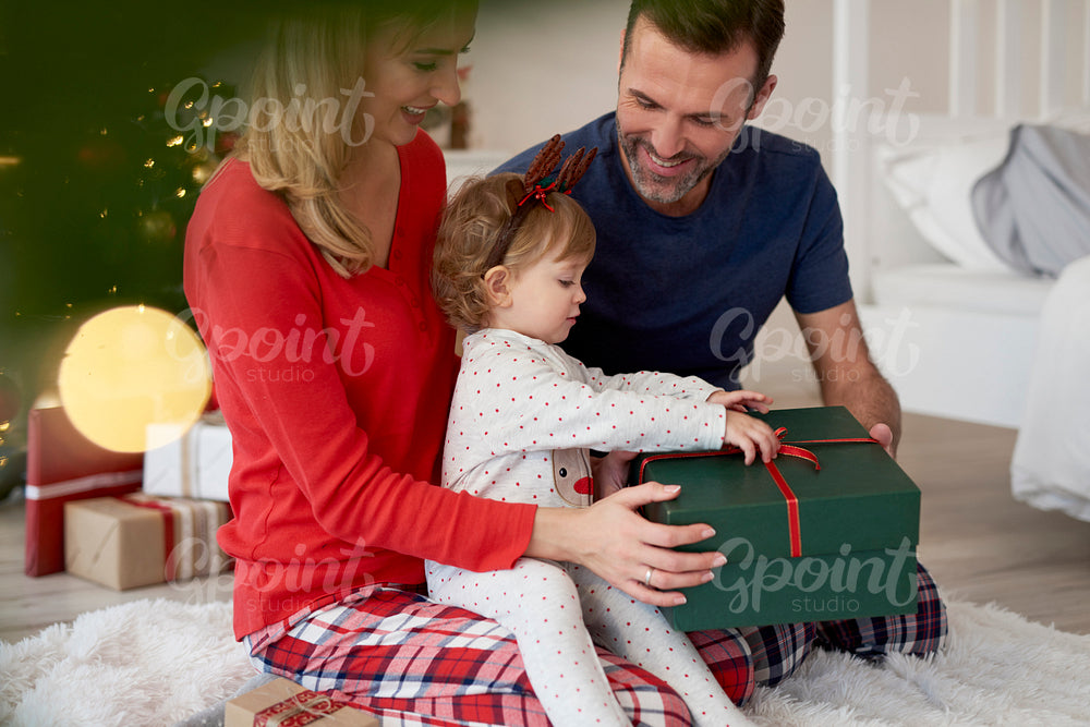 Baby opening Christmas present with parents