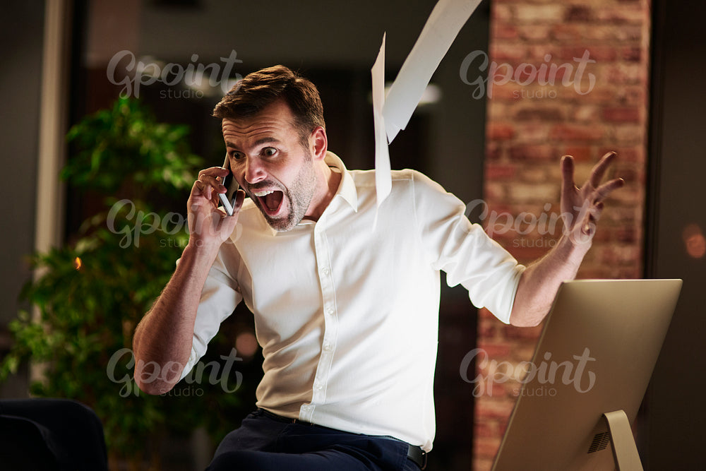 Screaming man talking by mobile phone in office