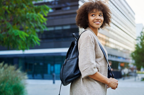 Rear view of smiling woman walking with backpack outdoors