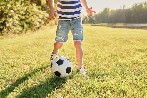 Little boy playing football on the grass