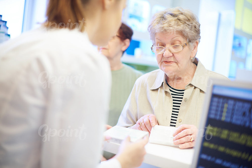 Senior customer at cash register with pharmacist