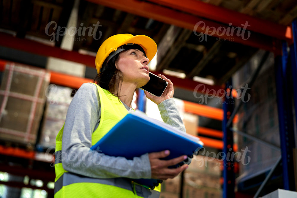 Adult caucasian woman talking by mobile phone in warehouse 