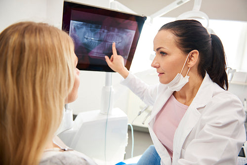Female dentist pointing at patient's x-ray