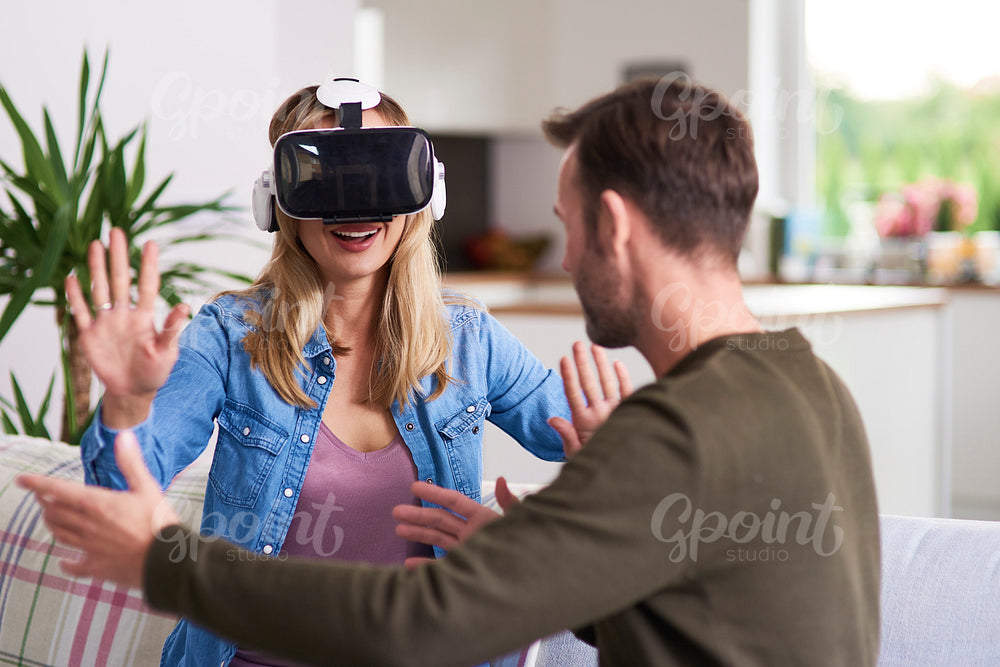 Modern woman using virtual reality simulator in living room