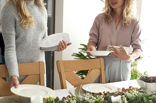 Two unrecognizable caucasian women preparing table for Christmas Eve