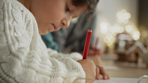 Handheld video of little boy focused on writing letter to Santa Claus