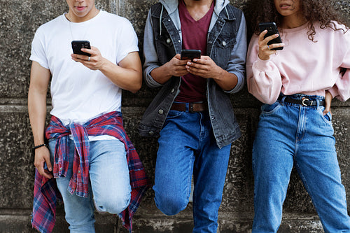 Front view of unrecognizable young people standing with mobile phones