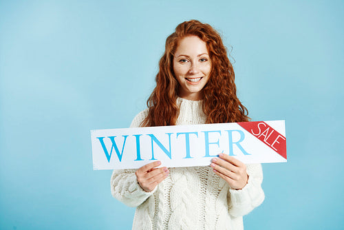 Portrait of smiling girl showing banner of winter sale