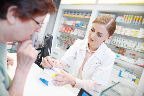 Young pharmacist helping elderly customer