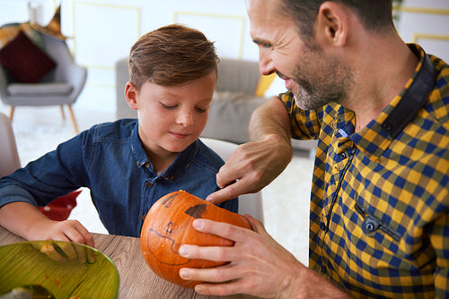 Boy carving pumpkins with father for Halloween