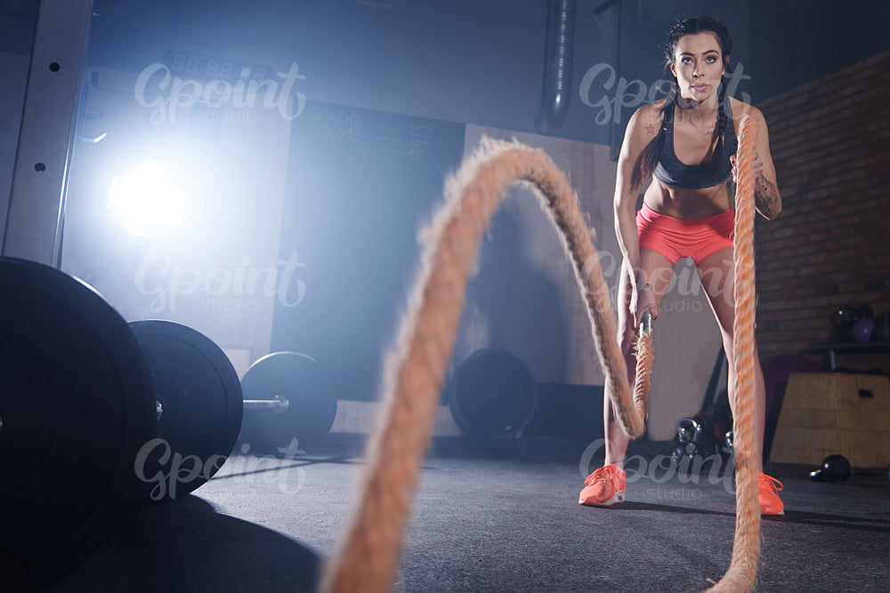 Young woman tossing ropes at gymnasium