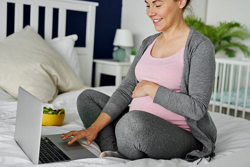 Cheerful pregnant woman using computer