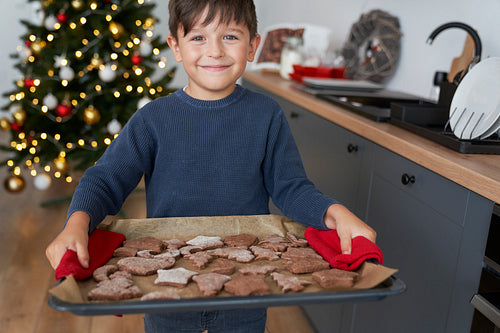 Boy holding a tray full of homemade gingerbread cookies