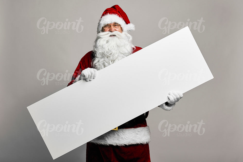 Caucasian Santa Claus on grey background holding a long copy space sign