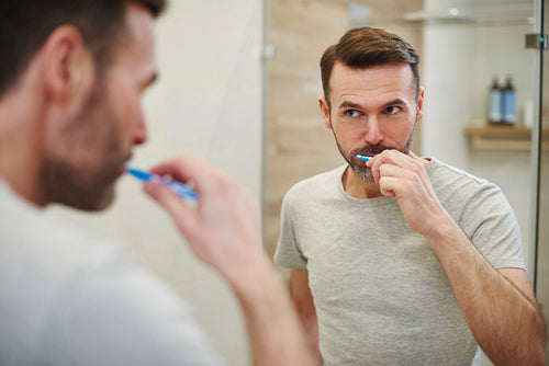 Man cleaning  teeth in bathroom