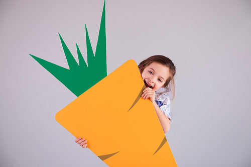 Playful girl eating a big carrot