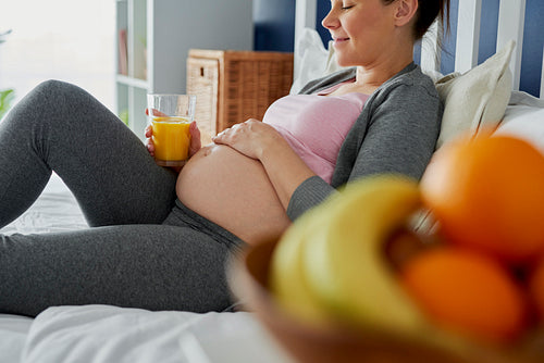Pregnant woman drinking freshly pressed juice in bed