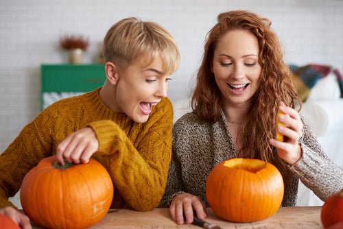 Playful girl carving pumpkin for halloween