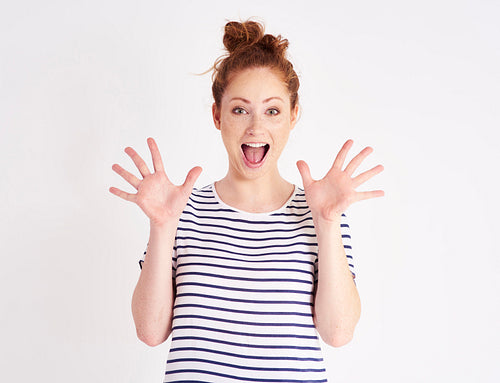Excited woman with hands raised shouting at studio shot