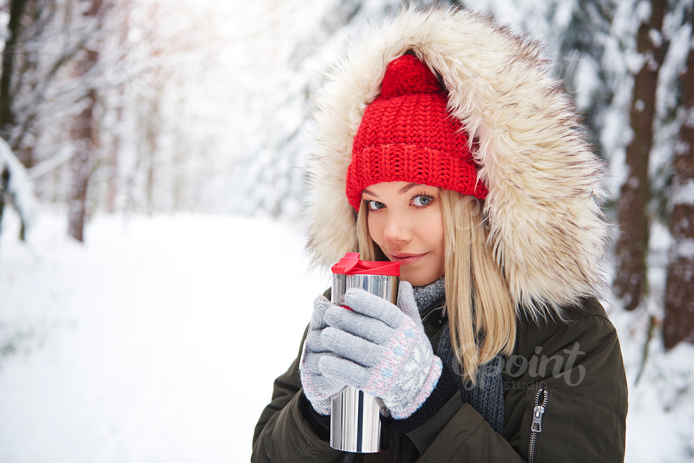 Happy woman wearing warm clothes drinking hot tea