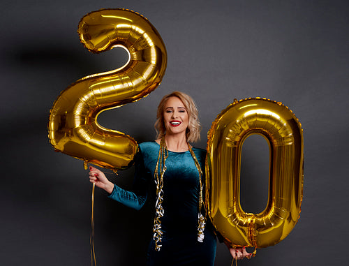 Woman with golden balloons building the figure „20”