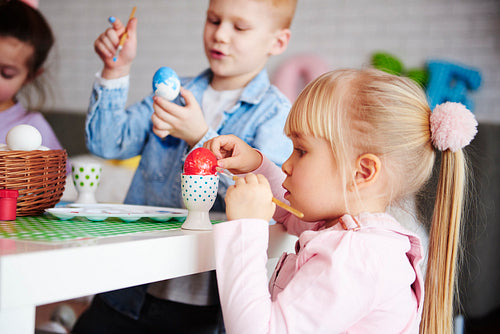 Close up of focused girl decorating easter egg