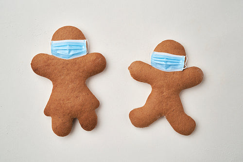 Top view of two gingerbread man with face masks