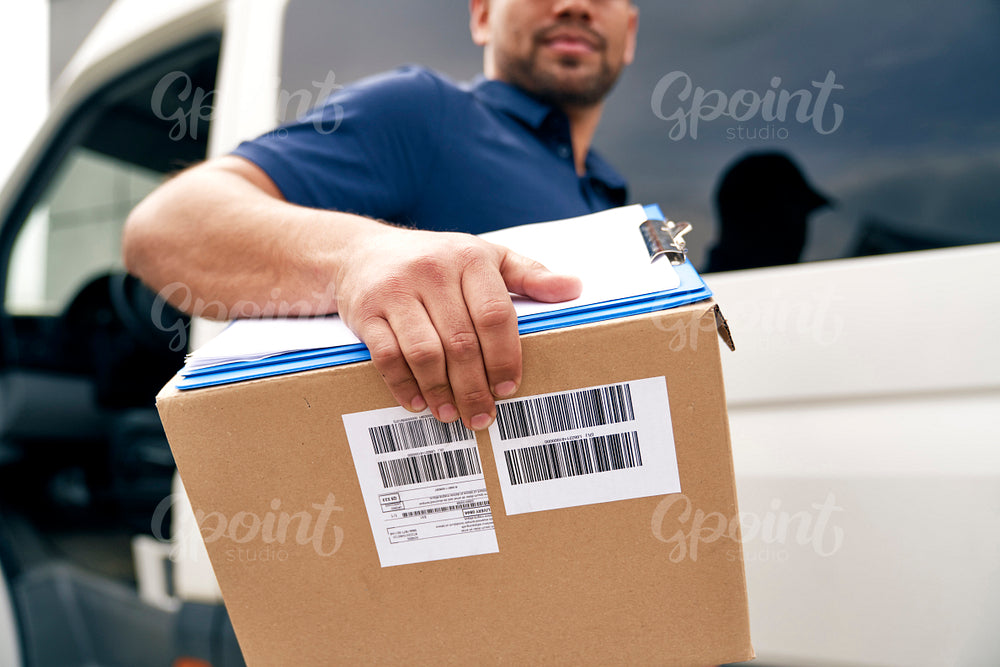 Close up of courier holding cardboard box for delivery