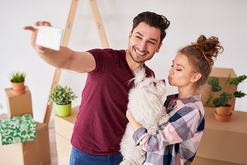 Happy couple with dog making a selfie in new home