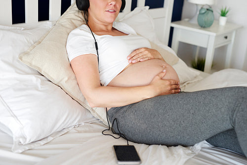 Pregnant woman listening music from mobile phone