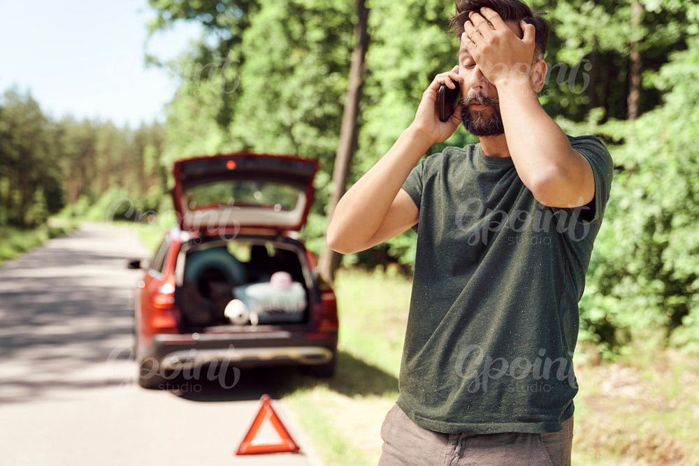 Man with car problems in forest using a mobile phone