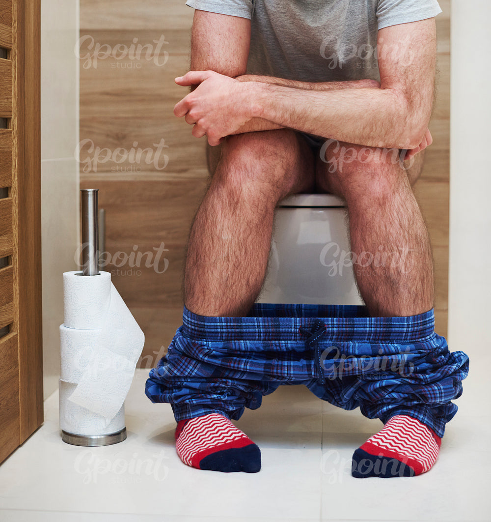 Low section of man defecating in the toilet