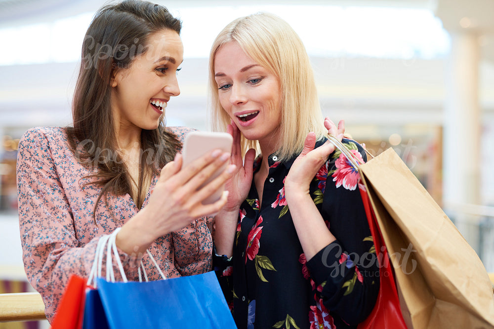 Girls with mobile phone choosing the next direction of shopping