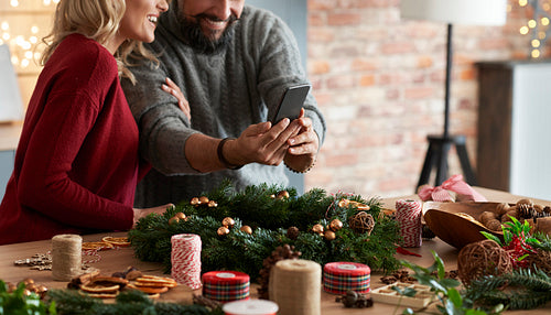 Couple taking photos of the Christmas wreath on the table