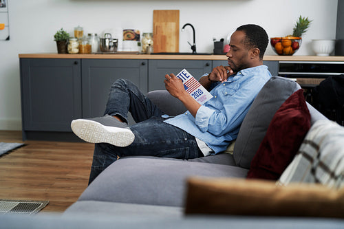 Man sitting on sofa and browsing information leaflet