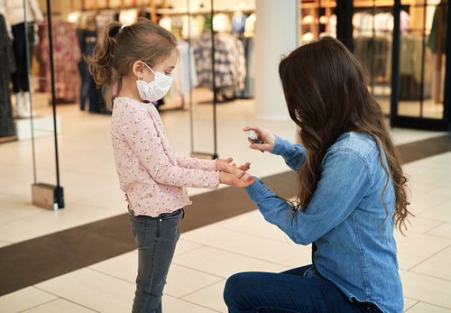 Mother sanitizing her daughter's hands with antibacterial hand spray