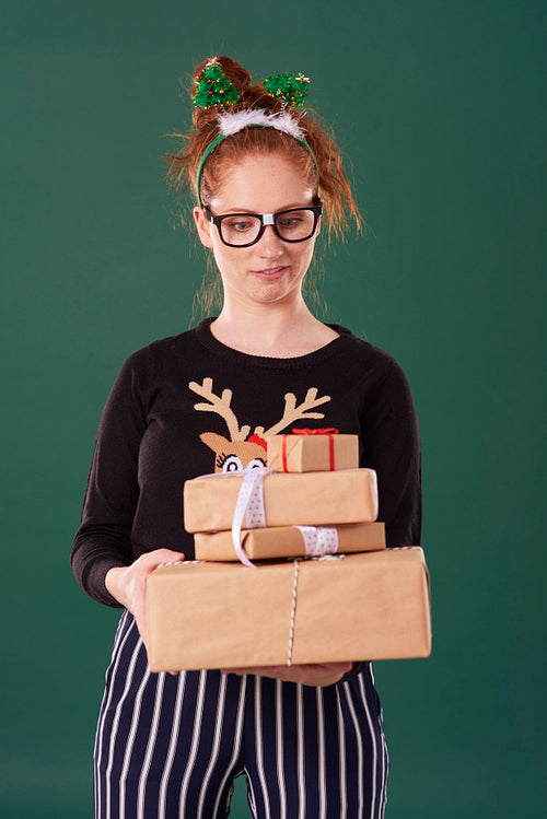 Displeased woman holding stack of christmas present