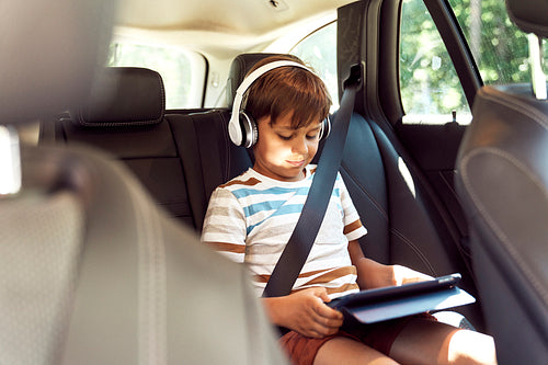 Boy with digital tablet while riding in car