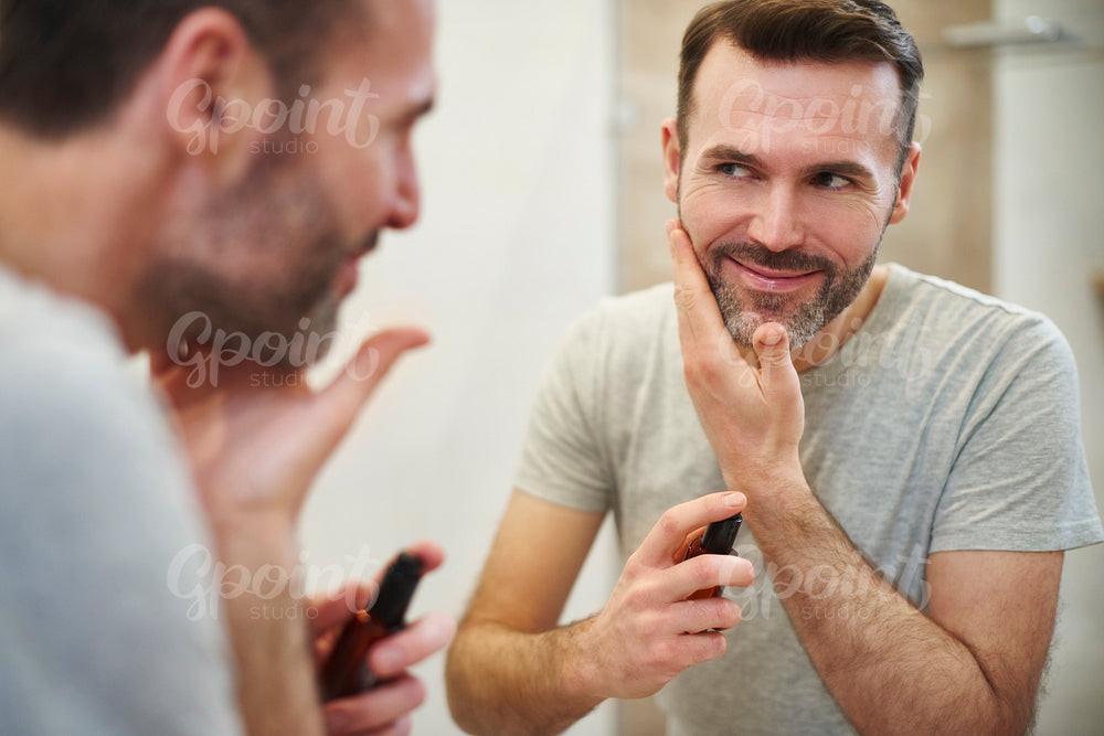 Smiling man applying beauty product on his face