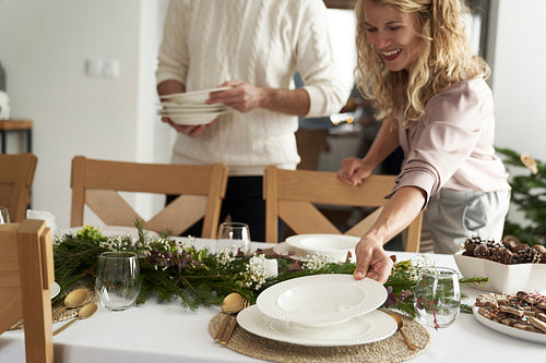 Cheerful caucasian couple preparing the table for Christmas Eve